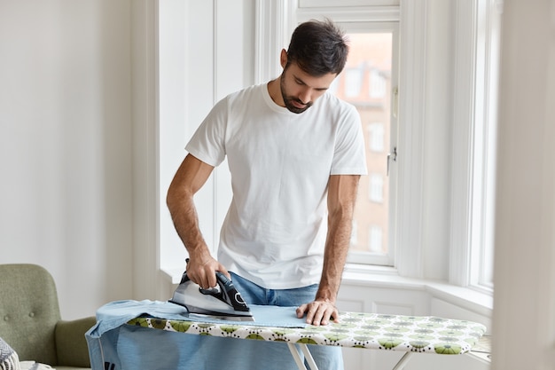 Homme barbu travaillant dur habillé en t-shirt blanc