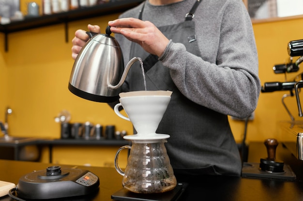 Homme barista avec verser de l'eau dans le filtre à café