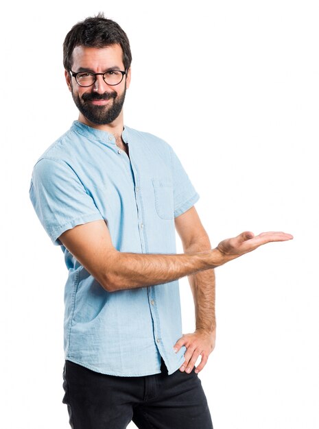 Un homme beau avec des lunettes bleues présentant quelque chose