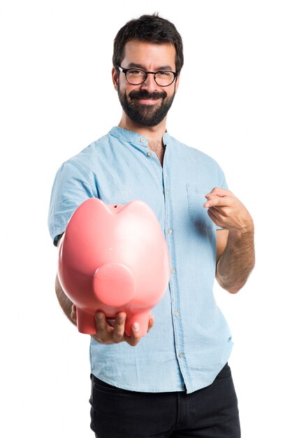 Homme beau avec des lunettes bleues tenant une tirelire