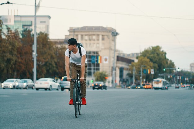 Homme, bicyclette voyageant, dans, urbain, ville, tenant mains, sur, guidon