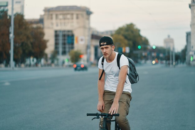 Homme, bicyclette voyageant, dans, urbain, ville, tenant mains, sur, guidon