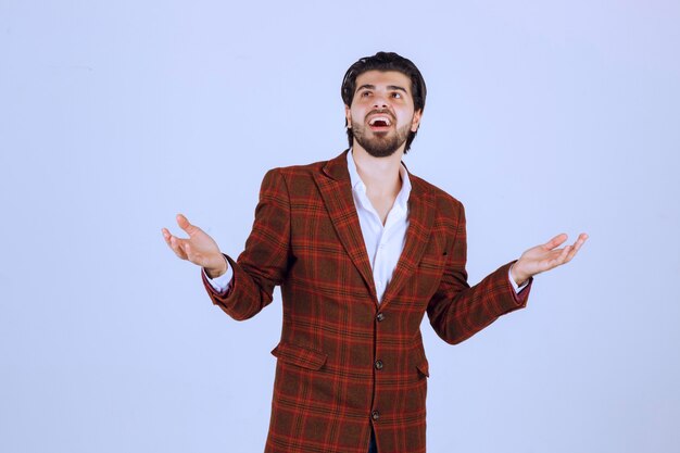 Homme en blazer à carreaux ayant un discours dans la scène et présentant quelque chose ci-dessus.