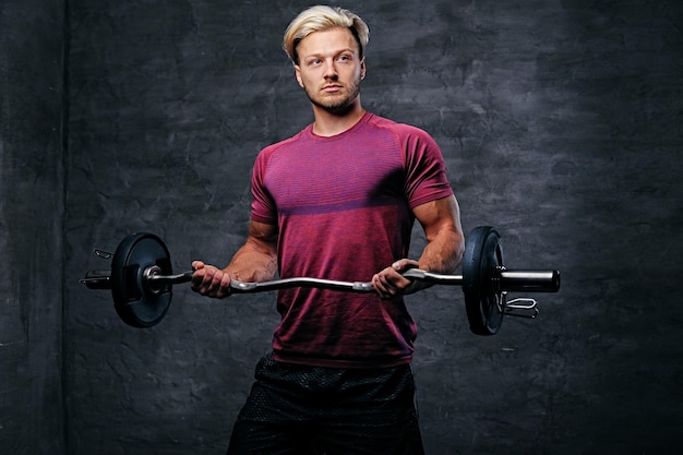 Homme blond athlétique faisant un entraînement de biceps avec une barre.