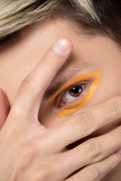 Photo gratuite homme blond portant un eye-liner orange