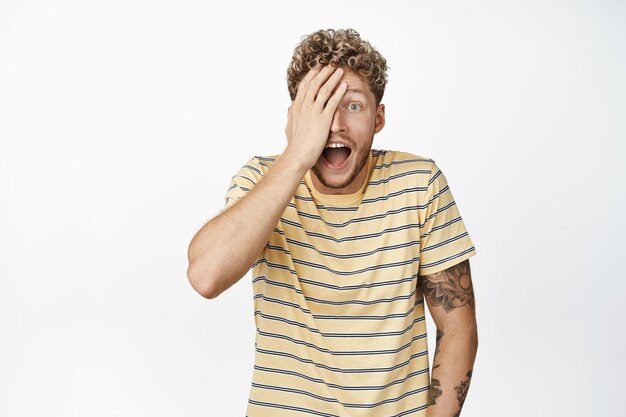 Un homme blond riant excité qui a l'air surpris et étonné d'entendre de grandes nouvelles réagissant à une surprise géniale debout sur fond blanc