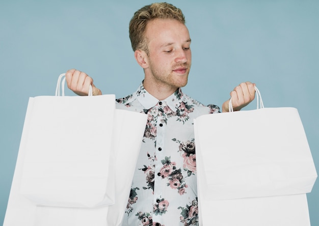 Homme blond avec des sacs à provisions sur fond bleu