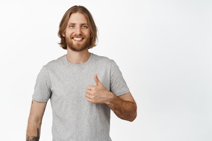 Photo gratuit homme blond souriant montrant le pouce vers le haut, approuve et hoche la tête, comme quelque chose de bien, excellent choix, louange, compliment, debout sur blanc
