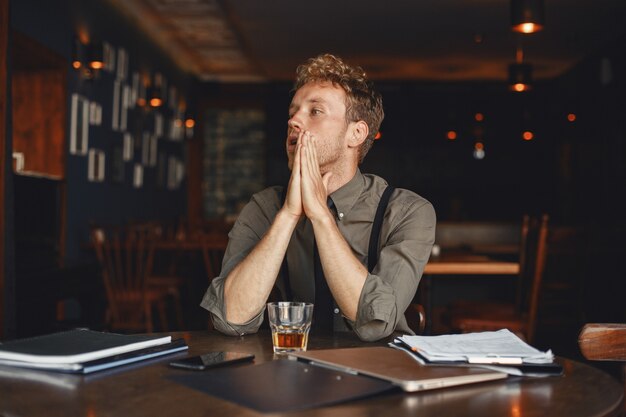 L'homme boit du whisky. Homme d'affaires lit des documents. Réalisateur en chemise et bretelles.