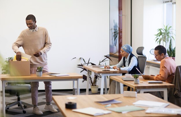 Homme avec boîte d'effets personnels s'installant dans son nouveau travail de bureau