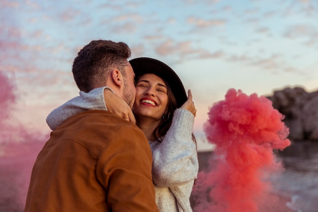 Homme avec une bombe de fumée embrassant une femme sur la joue