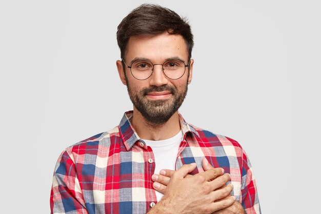 Un homme de bonne humeur sympathique et attrayant garde les deux paumes sur le cœur, exprime son amour aux gens, a plaisir à l'expression du visage