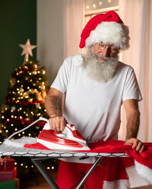 Homme en bonnet de noel repassant son costume