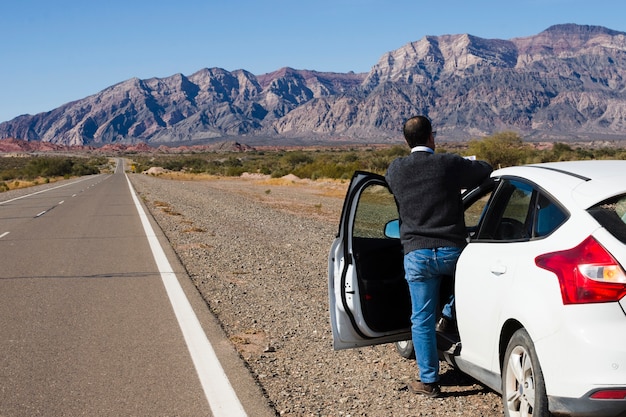 Homme sur le bord de la route en appréciant le paysage