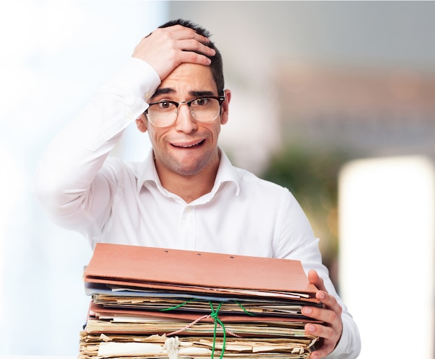 Homme Bored Regardant Une Pile De Papiers Avec Une Main Sur Son Front