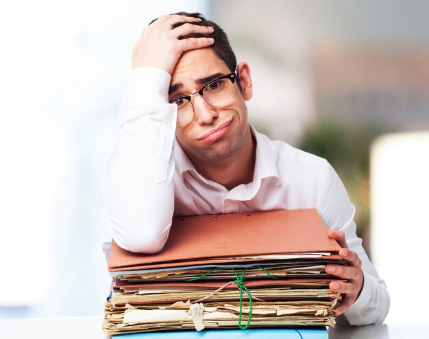 homme Bored regardant une pile de papiers avec une main sur son front
