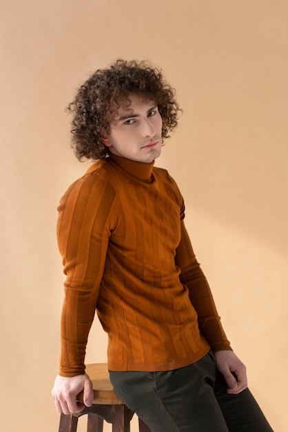 Homme bouclé avec chemisier marron posant