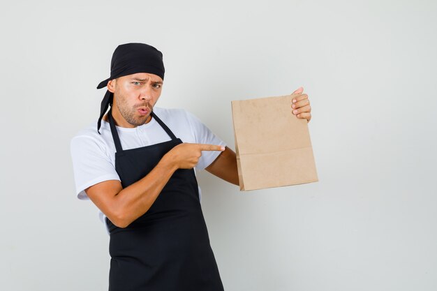 Homme de boulanger pointant sur un sac en papier en t-shirt