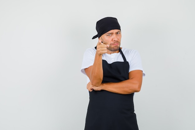 Homme de boulanger en t-shirt, tablier pointant vers la caméra et à la colère