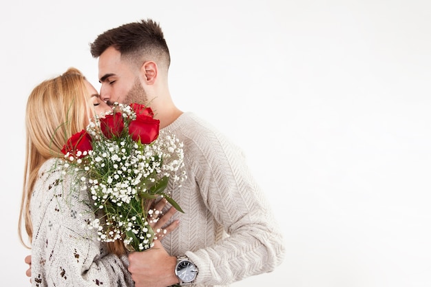 Homme avec bouquet embrassant femme