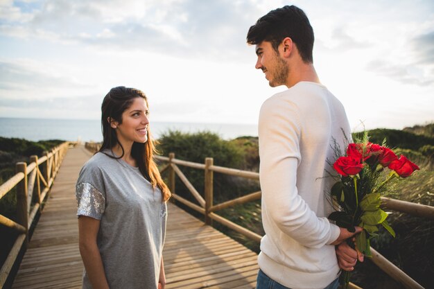 L&#39;homme avec un bouquet de roses sur son dos regardant sa petite amie