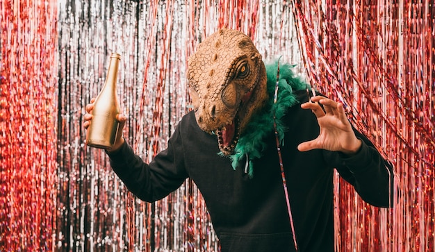 Homme avec bouteille de champagne en costume de dinosaure