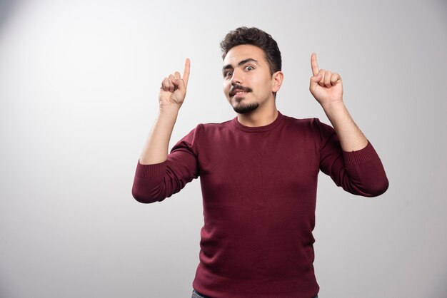 Un homme brune choqué montrant les doigts et posant.