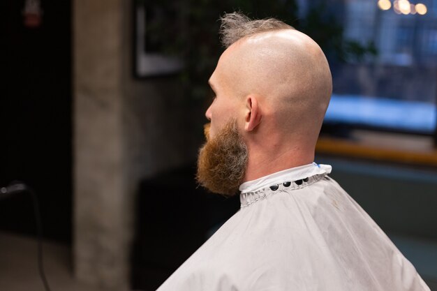 Homme brutal européen avec une barbe coupée dans un salon de coiffure