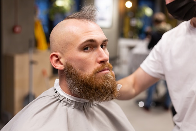 Homme brutal européen avec une barbe coupée dans un salon de coiffure