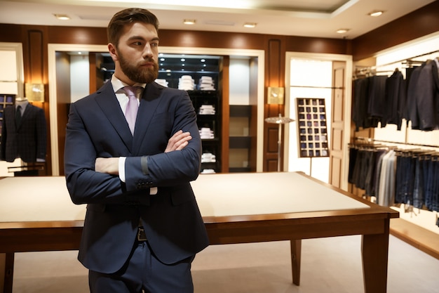 Homme calme debout près de la table avec les bras croisés