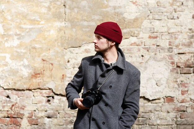 Un homme avec une caméra se tient devant un mur en ruine