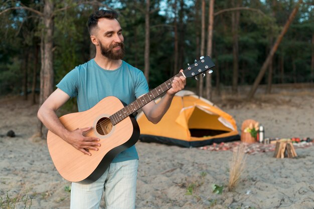 Homme de camping tir moyen jouer de la guitare