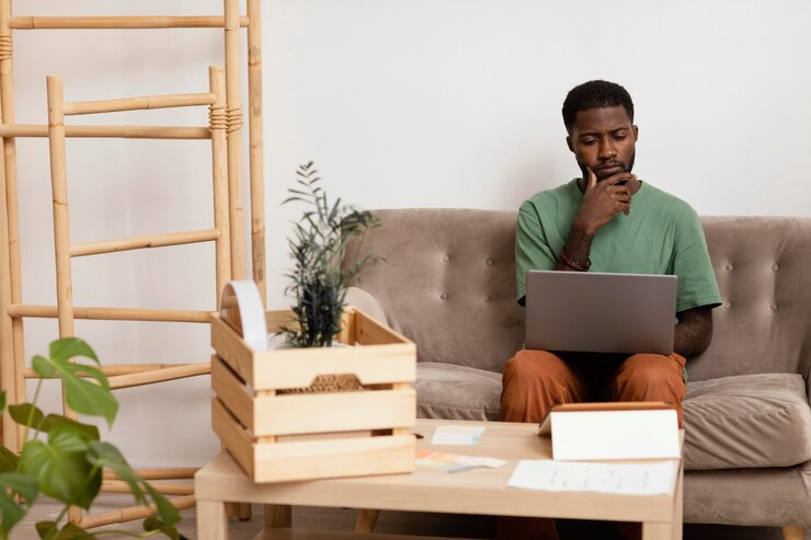 Photo gratuit homme sur le canapé faisant un plan pour redécorer la maison à l'aide d'un ordinateur portable