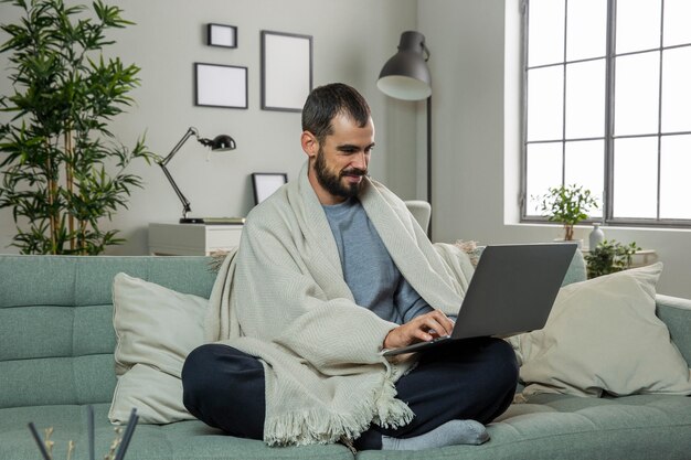 Homme sur canapé travaillant sur ordinateur portable