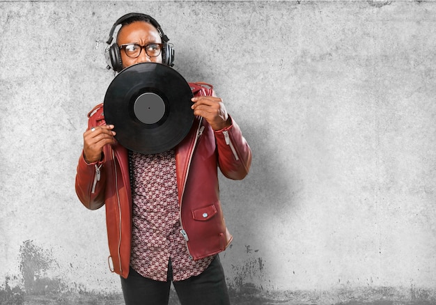 Photo gratuite l'homme avec un casque couvrant sa bouche avec un disque vinyle