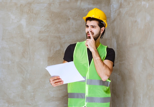 Homme en casque jaune et équipement vérifiant les fiches du projet