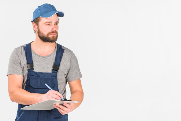 Homme en casquette et écriture générale dans le presse-papiers