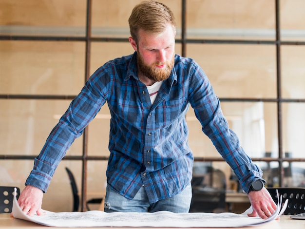 Homme caucasien barbu en regardant bleu imprimer au bureau