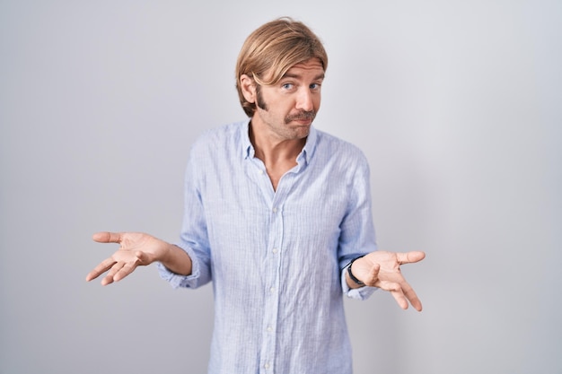 Photo gratuite homme caucasien avec moustache debout sur fond blanc désemparé et confus à bras ouverts aucun concept d'idée