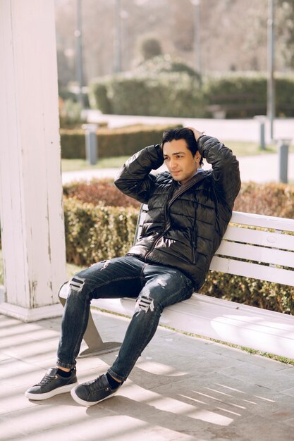 Homme célibataire assis sur le banc dans le parc et pensant. photo de haute qualité