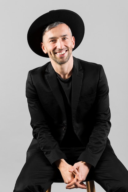 Photo gratuite homme, à, chapeau noir, sourire, et, séance chaise