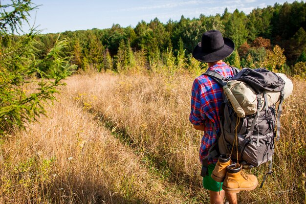 Homme avec chapeau voyageant dans le champ