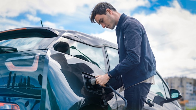 Homme chargeant sa voiture électrique à la station de charge