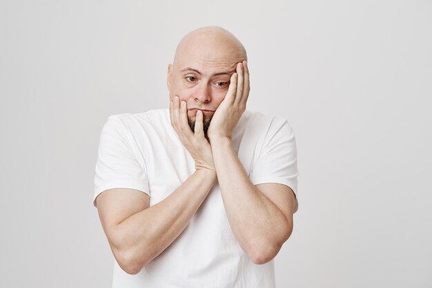 Homme chauve triste en détresse tenant les mains sur le visage et détourner le regard