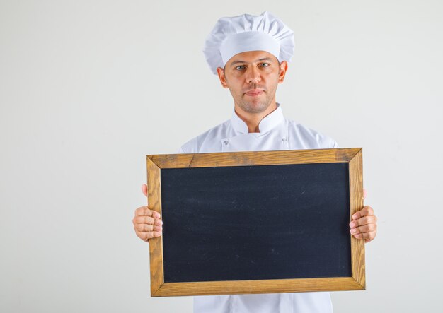 Homme chef cuisinier en chapeau et uniforme tenant tableau noir