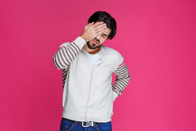 L'homme en chemise blanche a l'air épuisé et endormi.