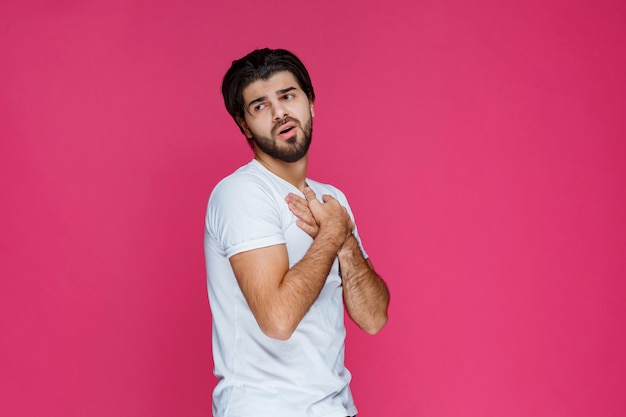 Homme en chemise blanche croisant les mains et se protégeant des dangers.