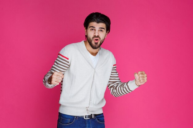 Homme en chemise blanche démontrant ses muscles et sa puissance de bras.