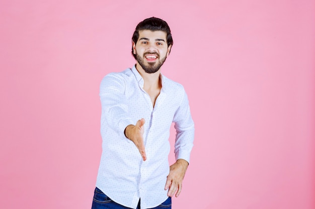 Homme en chemise blanche donnant la main à serrer.