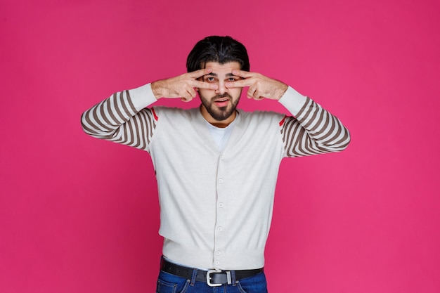 Homme en chemise blanche faisant signe de la main de la paix et envoi de message.